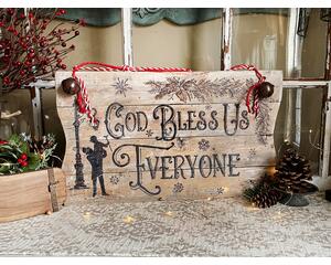 A wood Christmas Sign featuring Tiny Tim's quote "God Bless Us Everyone".  Scrooge and Tiny Tim stand  by a street lamp with snow falling. 